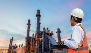 Engineering is use notebook check and standing in front of oil refinery building structure in heavy petrochemical industry